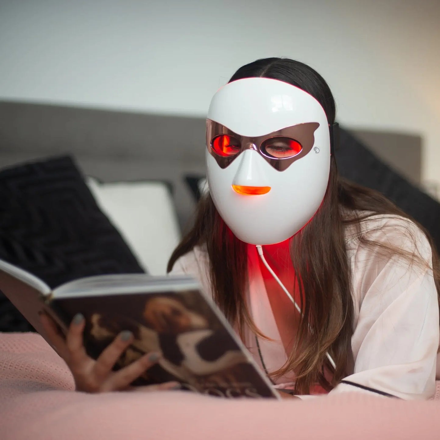 Silkemyk modell leser mens hun får behandling med en Silkemyk LED-Maske.